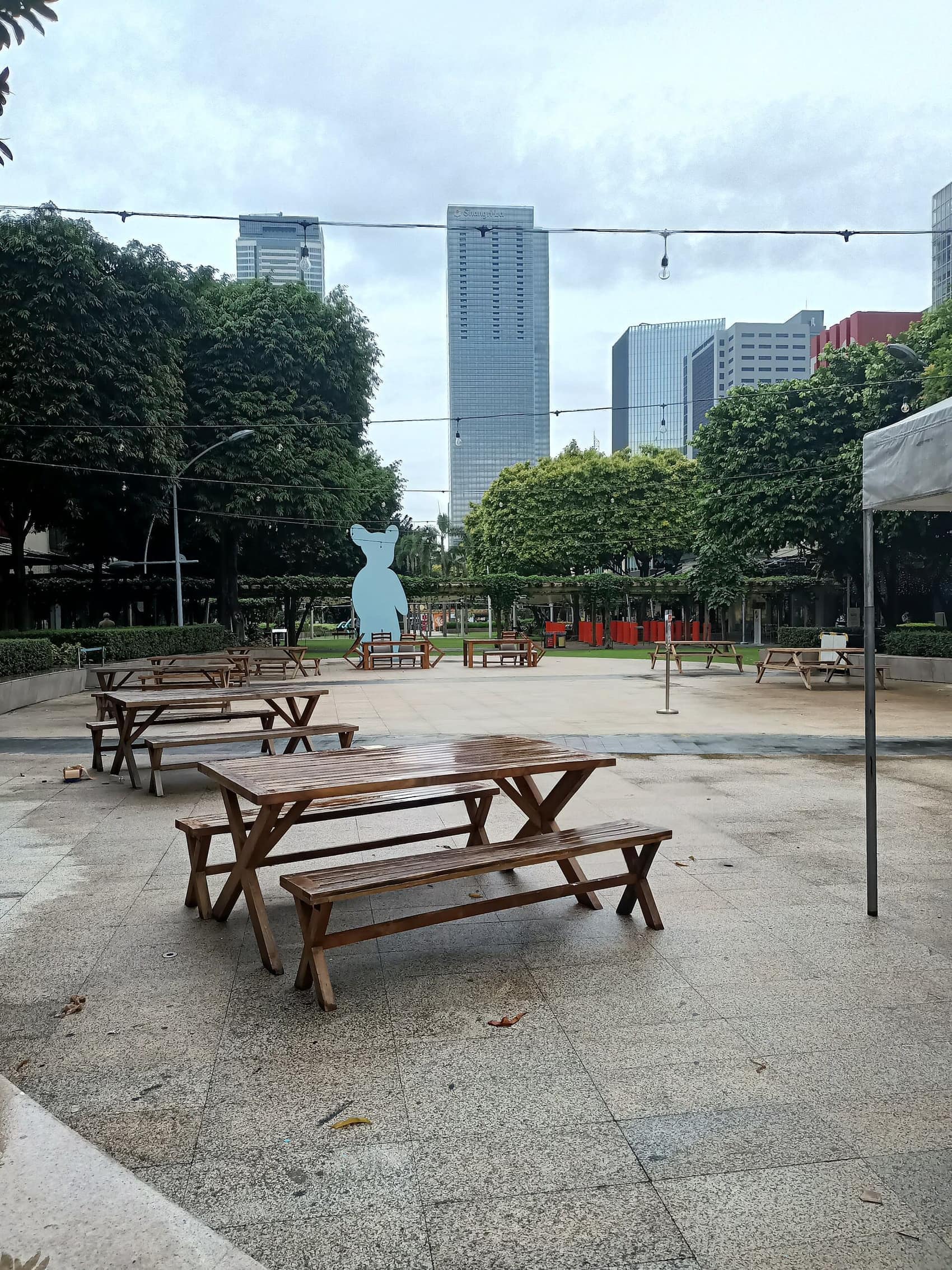 Picnic tables and shade trees on 9th Avenue, towers overhead