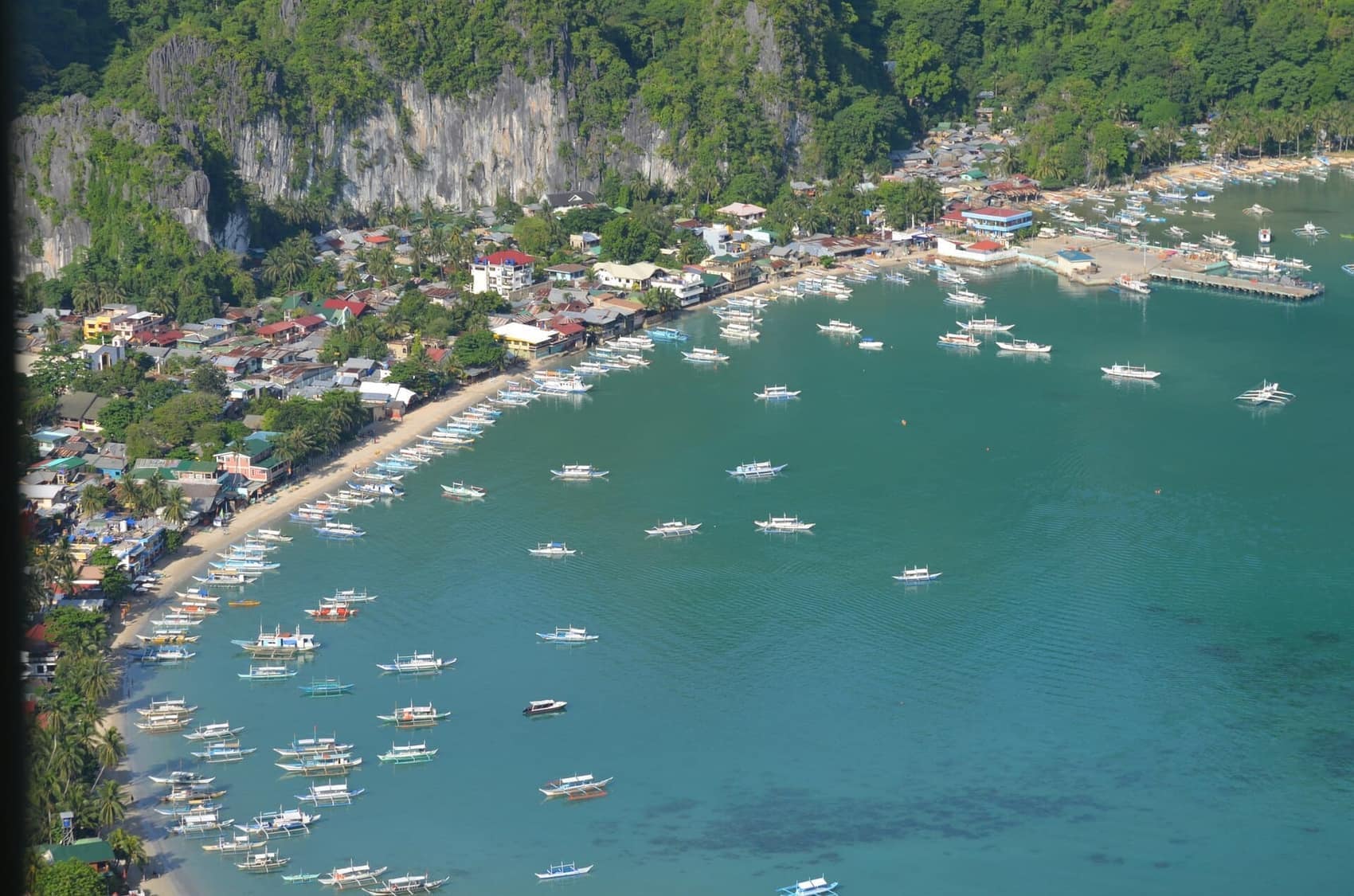El Nido town from above: the crescent bay, the boat fleet, and the islands stacked out to sea