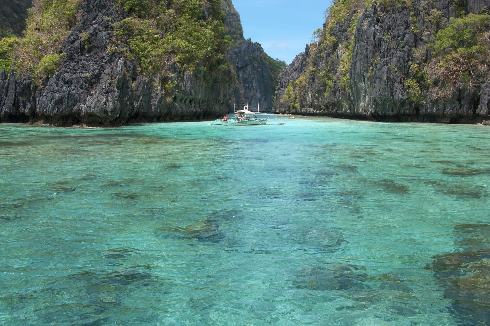A bangka anchored in glassy shallows inside one of the Bacuit Bay lagoons