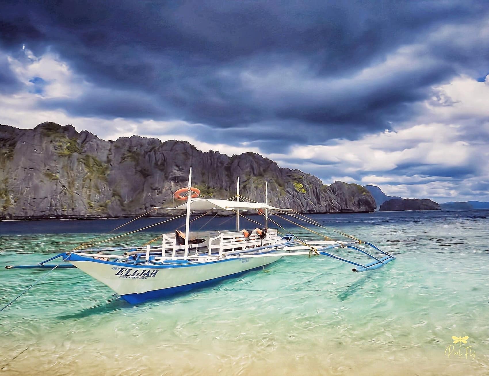 An outrigger bangka on turquoise water under a big Palawan sky