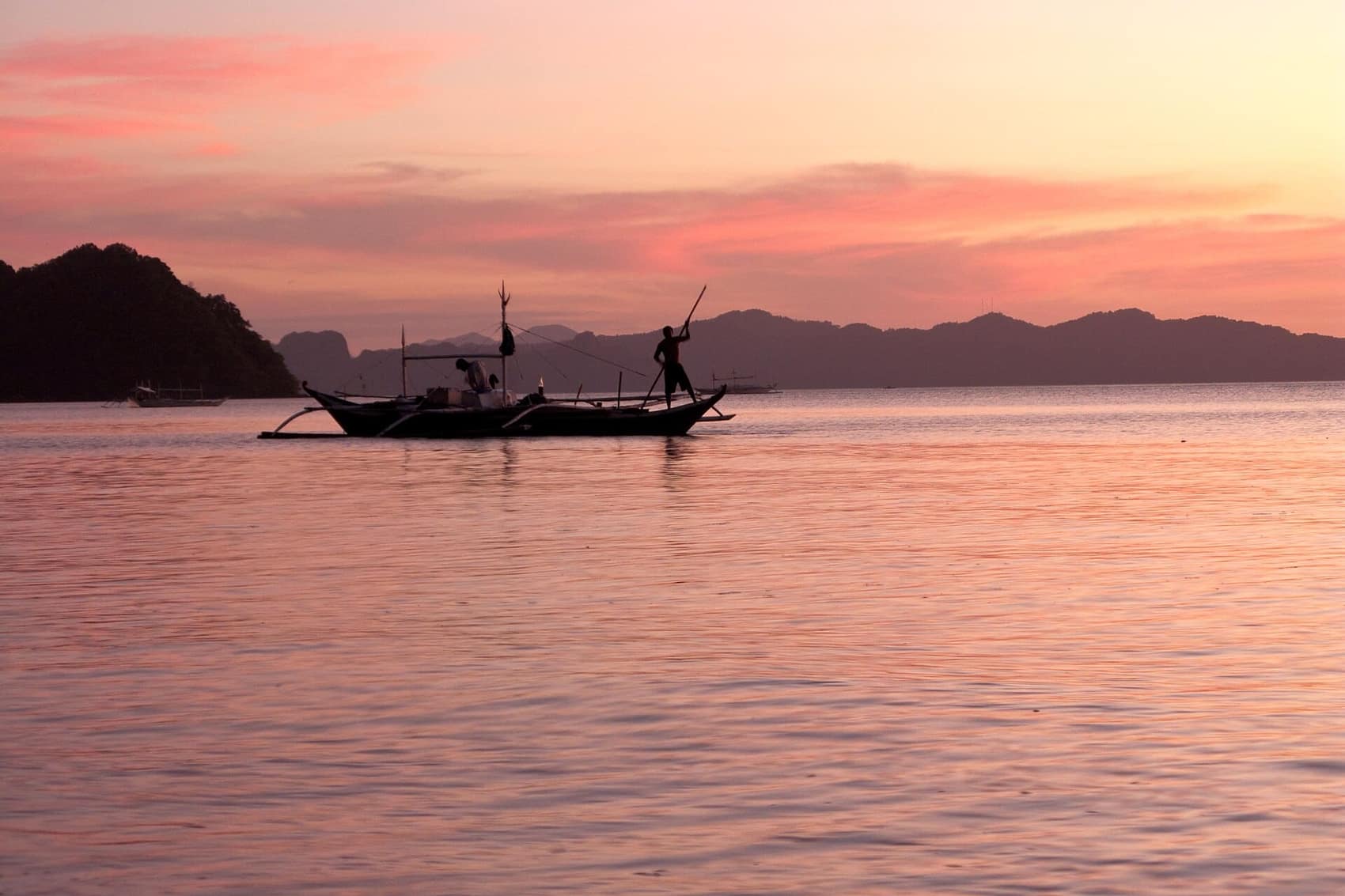 Pink twilight over Bacuit Bay with a bangka drifting on the flat water