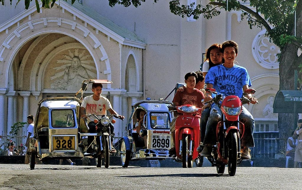 Motorcycle-and-sidecar tricycles working a Philippine main road: the standard short-hop taxi