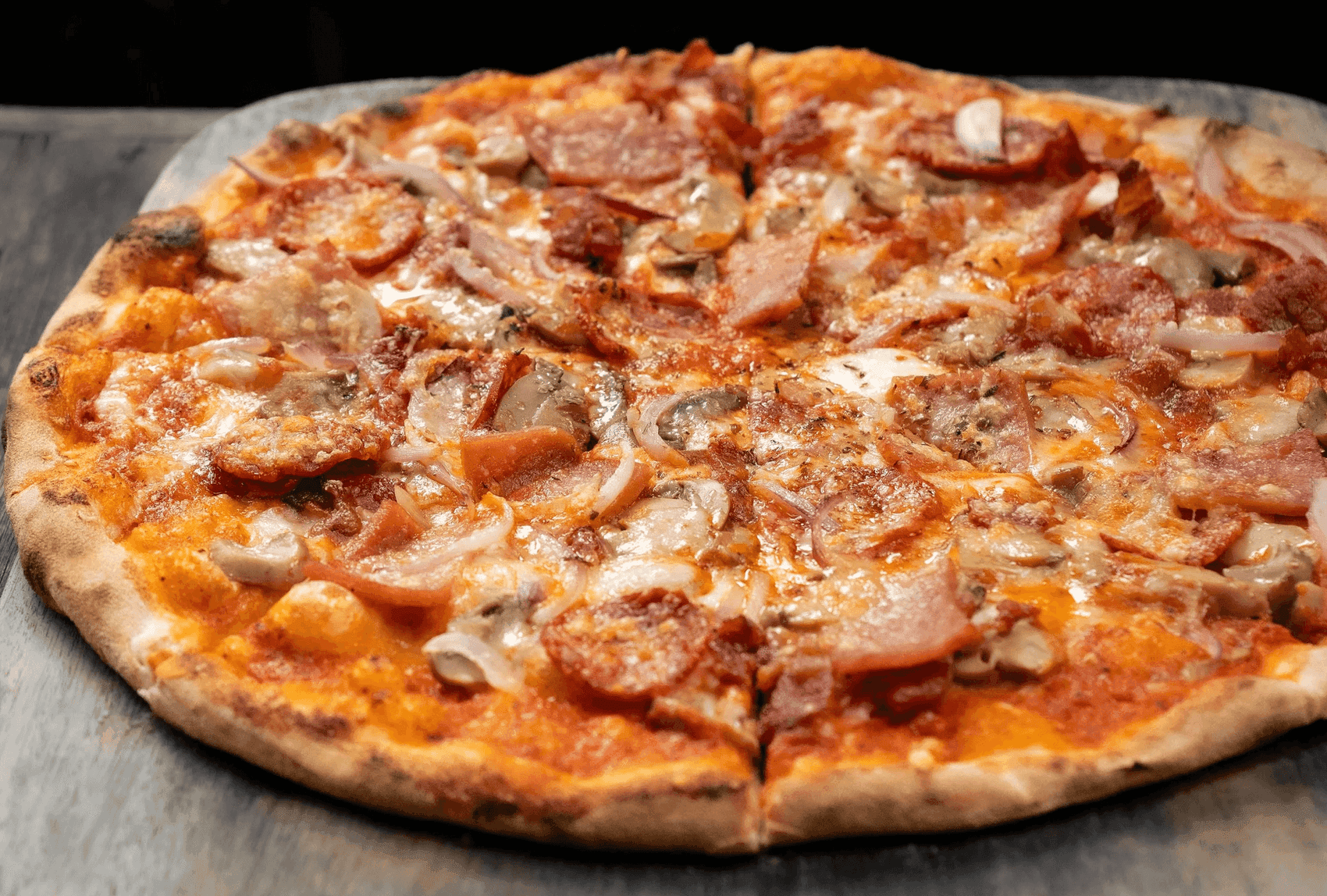 The Surfer's Pizza loaded with ham, bacon, sausage, spicy salami, mushroom and onion