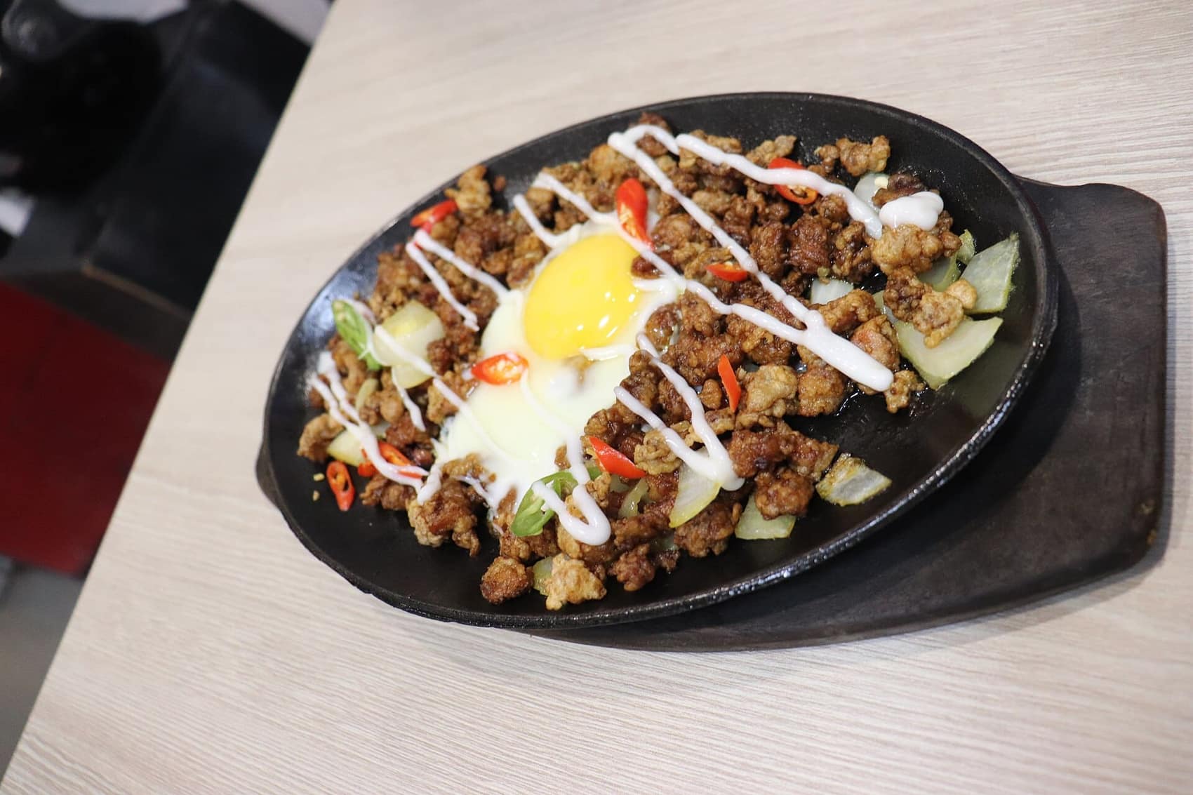 Sizzling sisig on a cast-iron plate with the egg still setting: Manam's signature, and the Philippines' best beer food