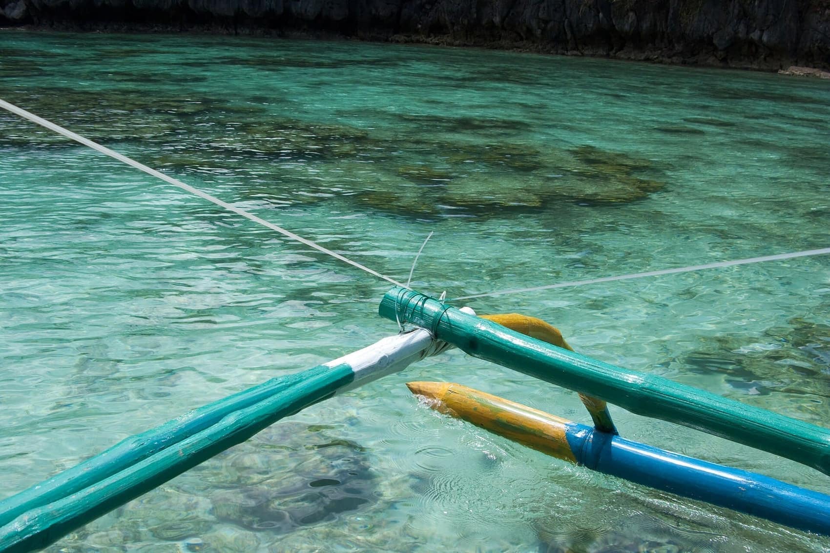 Outrigger arm skimming turquoise water on the run out to the islands