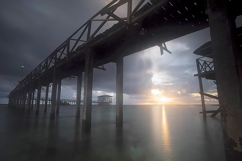 Beneath the boardwalk at dusk, long exposure. Siargao's reef flats at last light